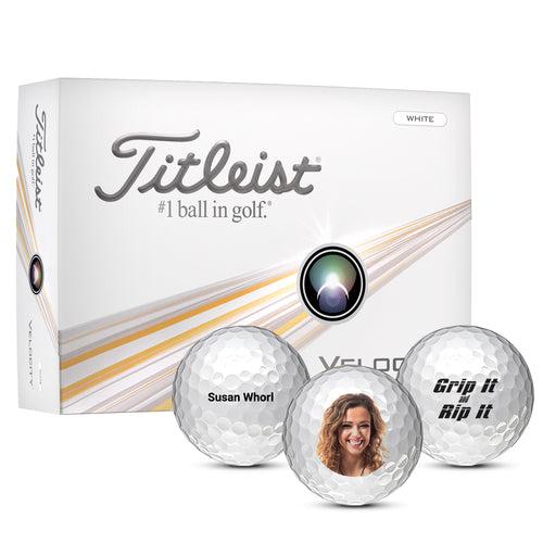 Titleist Velocity golf ball box with three custom balls in front.