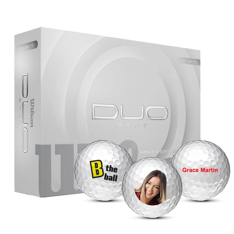 Box of Wilson DUO Soft golf balls with three custom balls in front. 